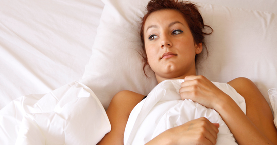 Woman laying in bed with the covers pulled up