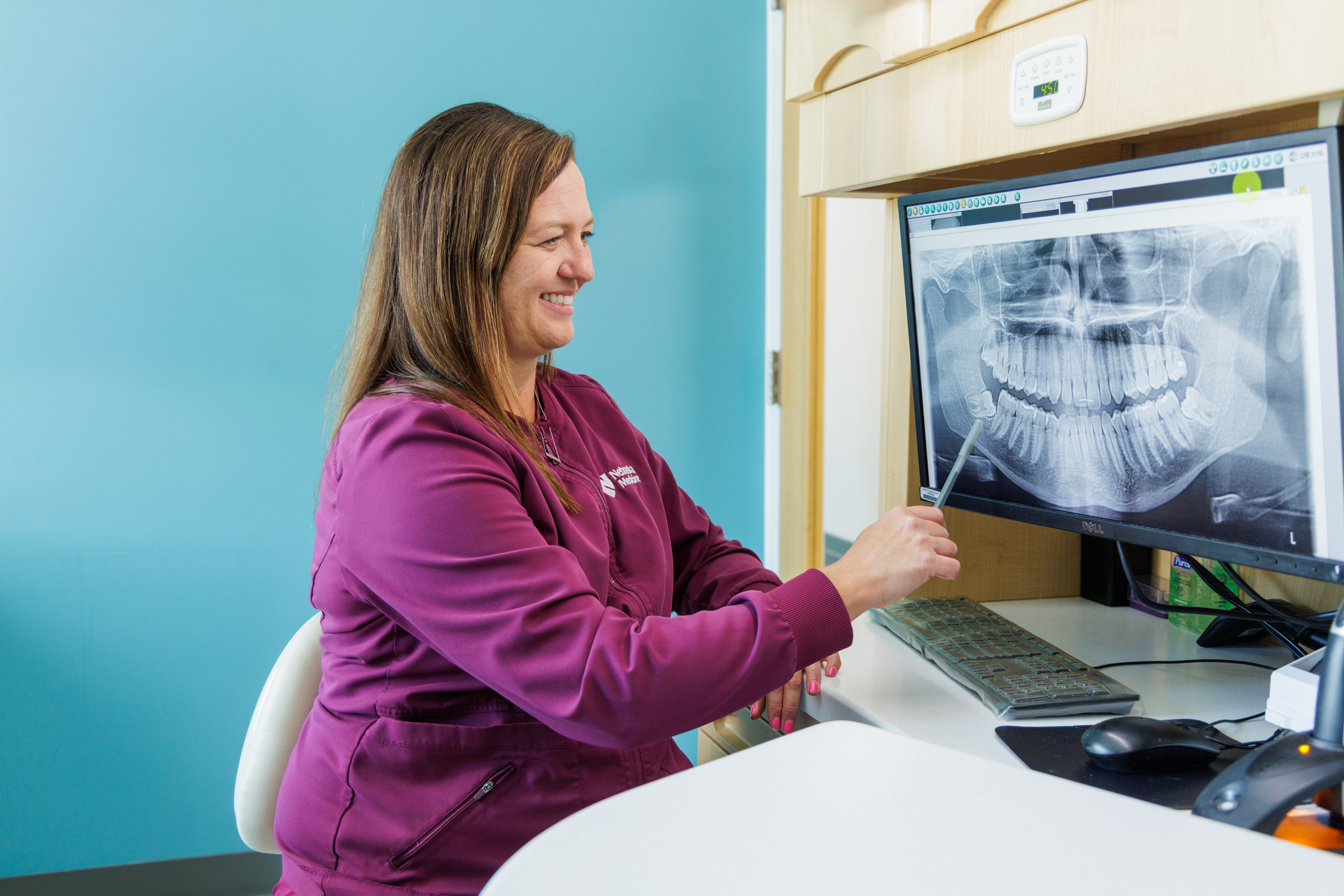 Dental hygienist looks at teeth x-ray