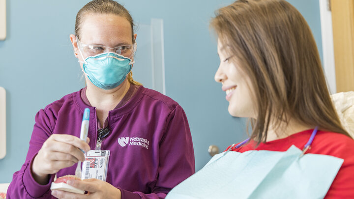 Dental hygienist educates patient in dental chair