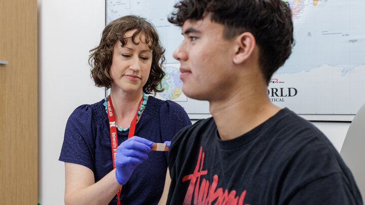 Medical professional with blue gloves places bandage on patient's upper arm