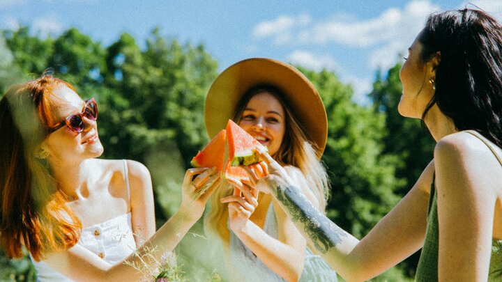 Three friends cheers with watermelon slices