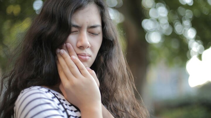 Person holding their cheek with toothache